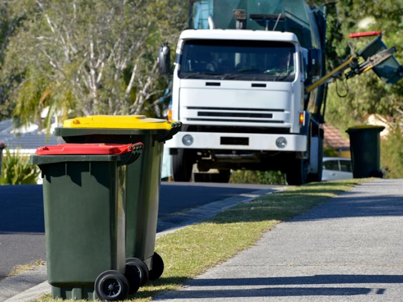 rubbish bins with rubbish truck in background lifting a bin